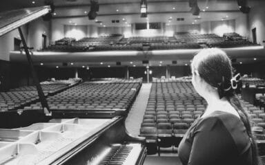 étudiante assise au piano regardant l'auditorium