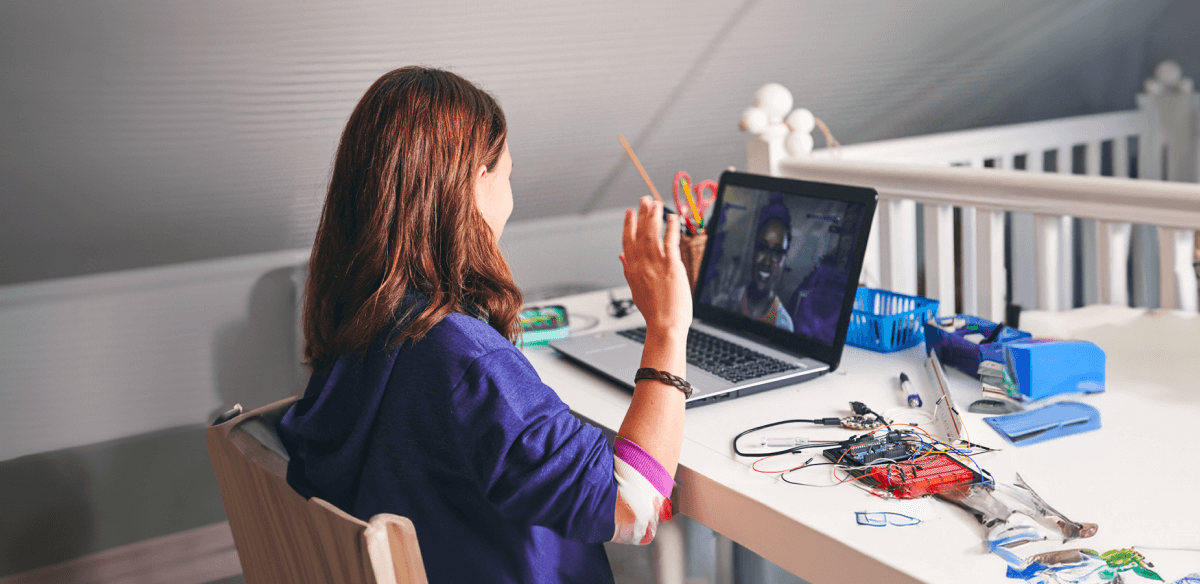 Une femme assise à un bureau, concentrée sur son ordinateur portable, entourée d'un espace de travail bien rangé.